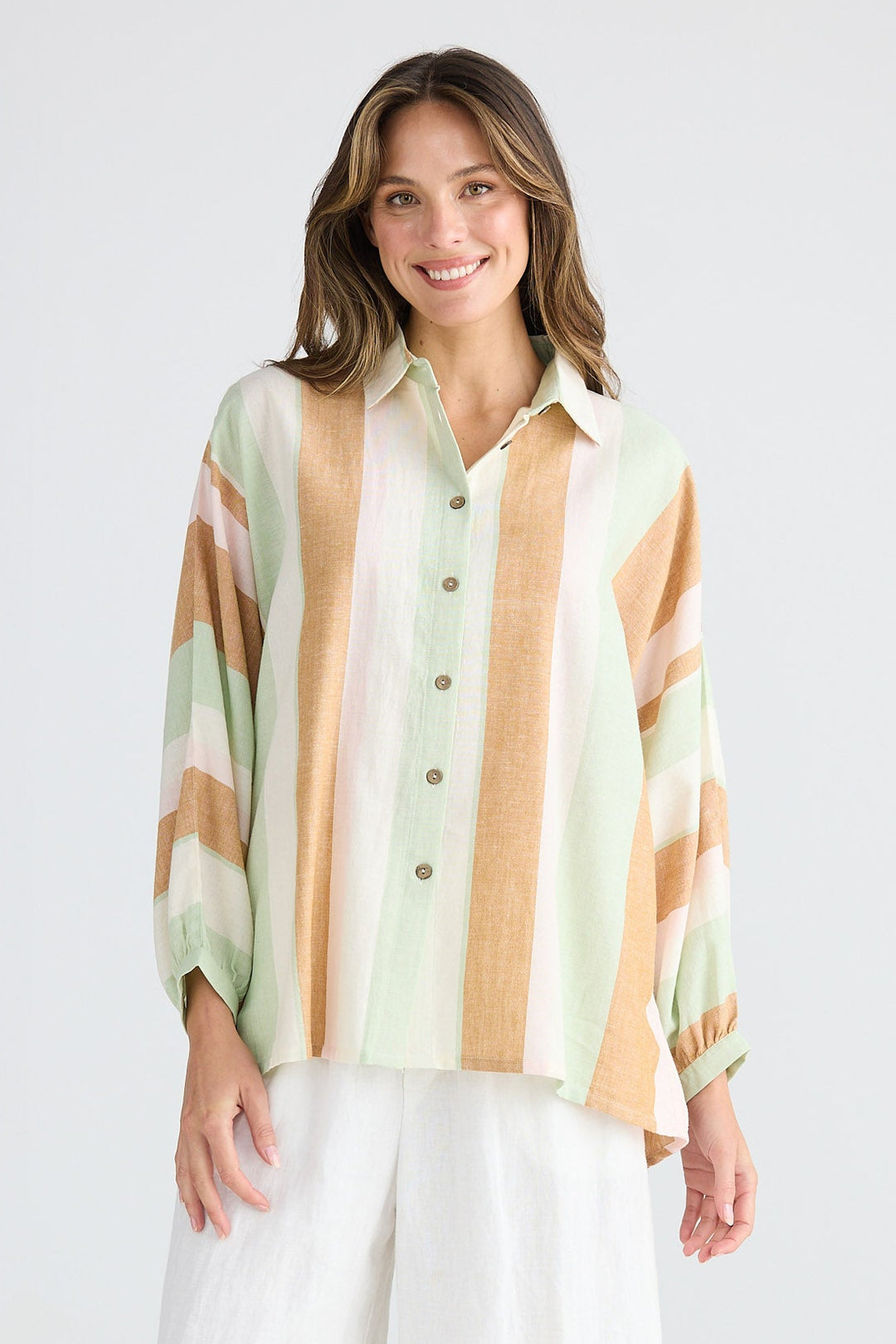 Woman wearing a striped shirt and white pants on a white background