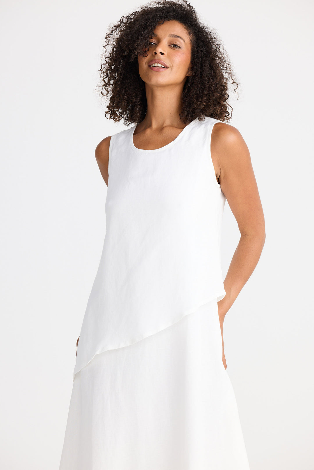 Woman wearing a white sleeveless dress against a plain background