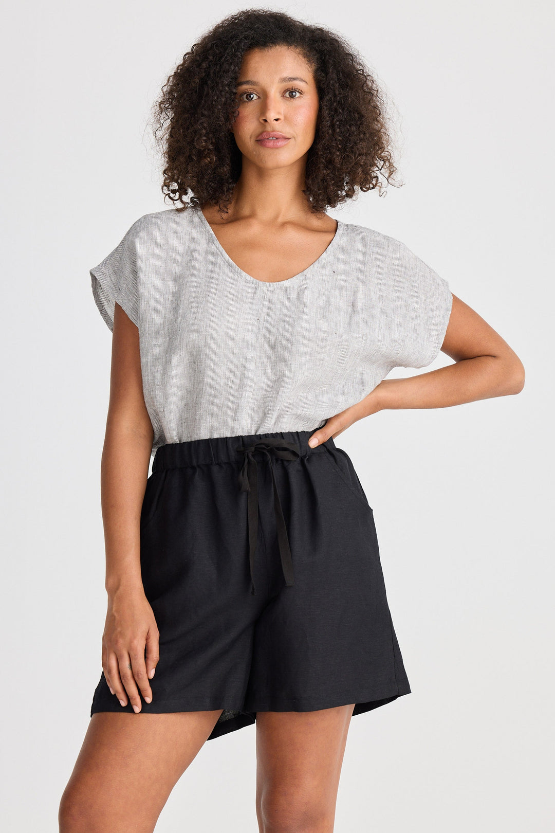 Woman wearing a light gray top and black shorts on a white background