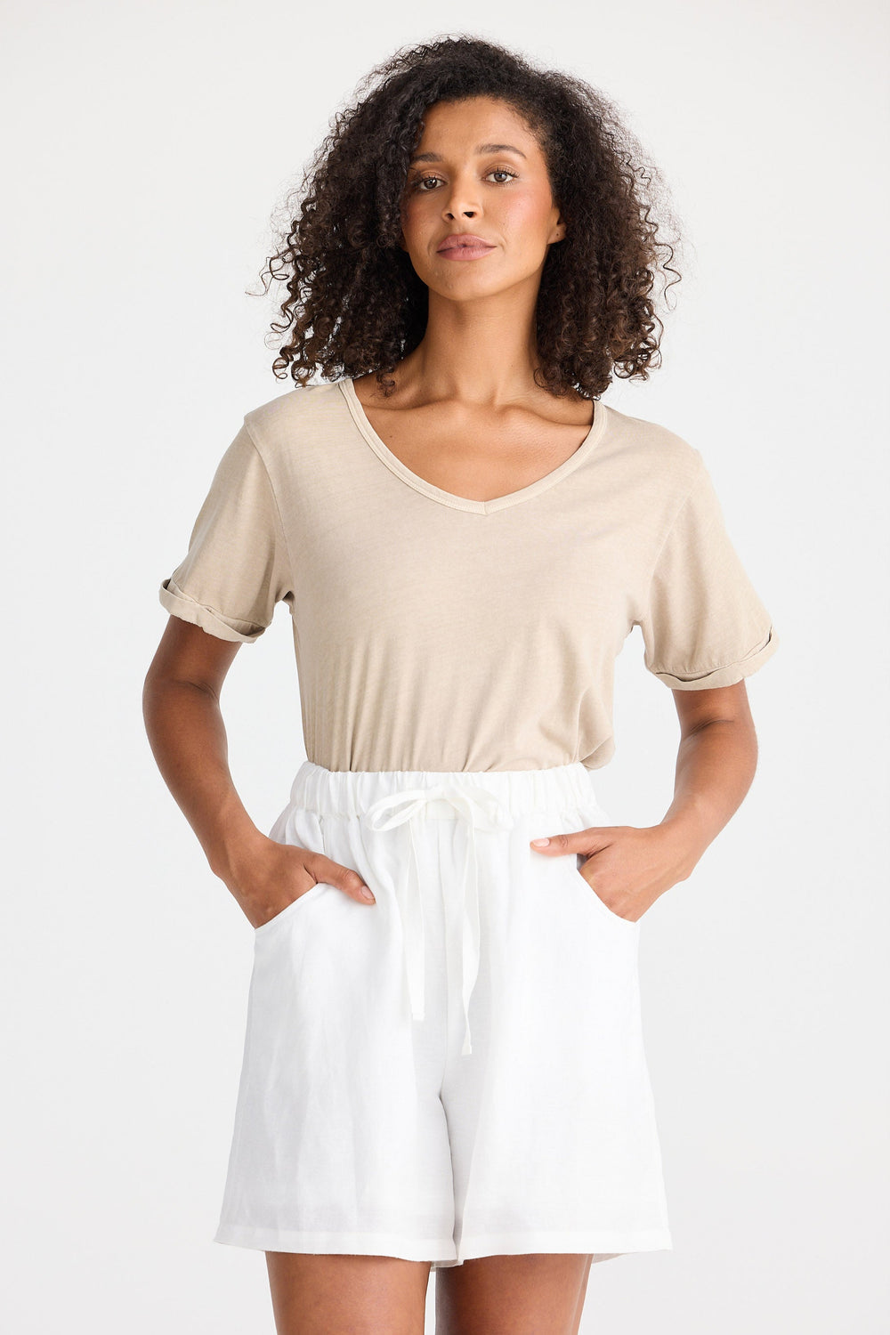 Woman wearing a beige top and white shorts on a plain background