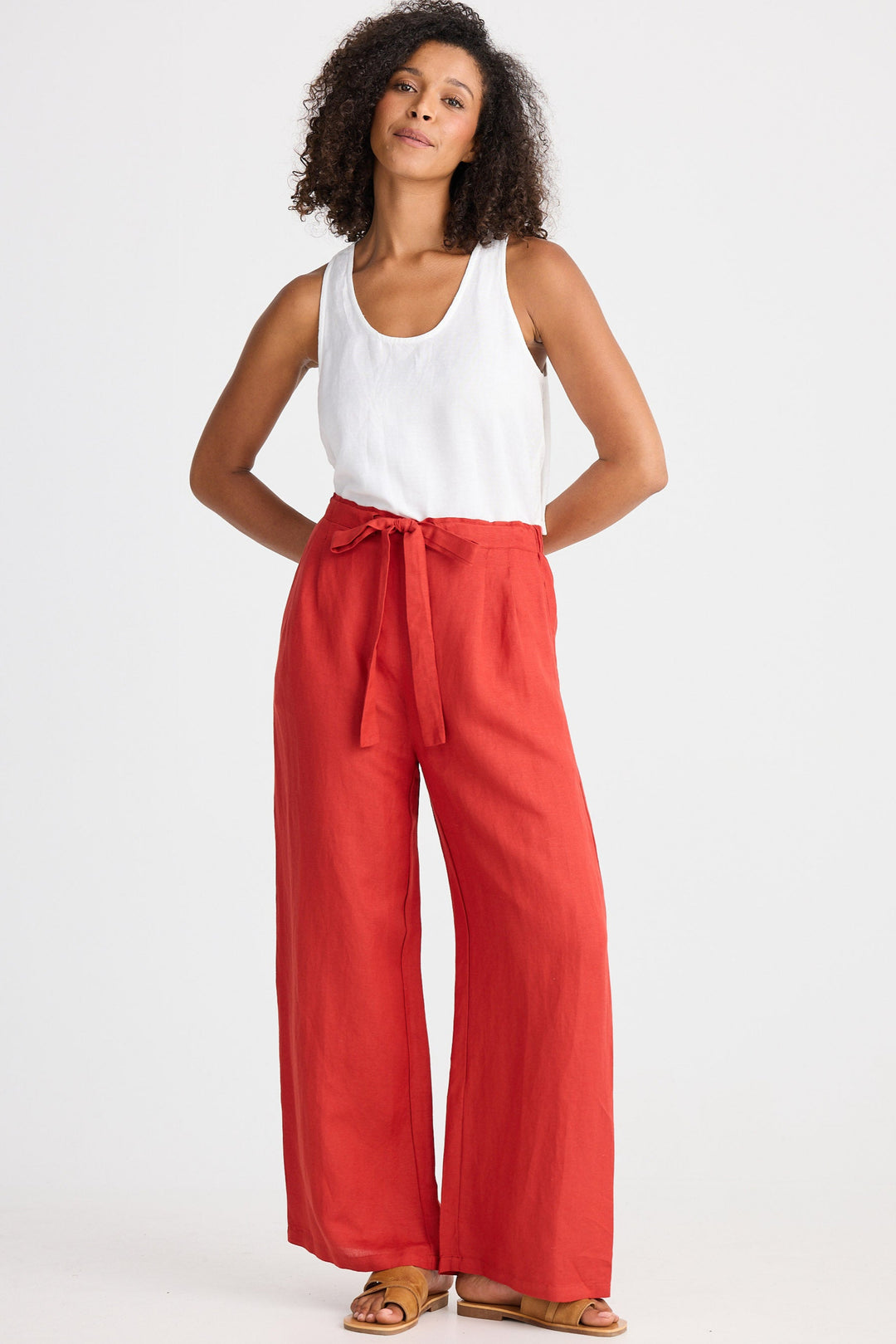 Woman wearing a white top and red wide-leg pants on a white background