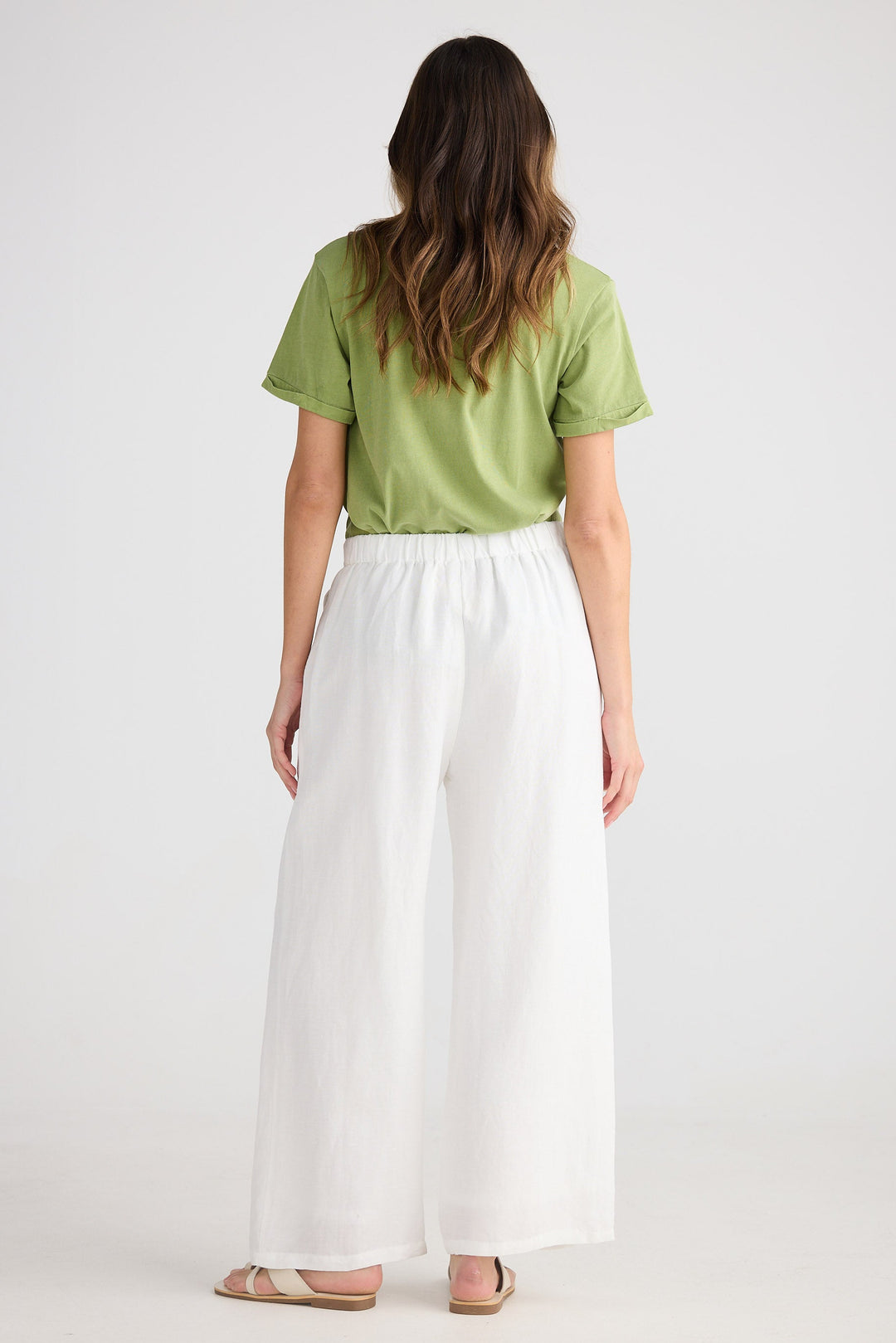Person wearing a green shirt and white skirt on a plain background