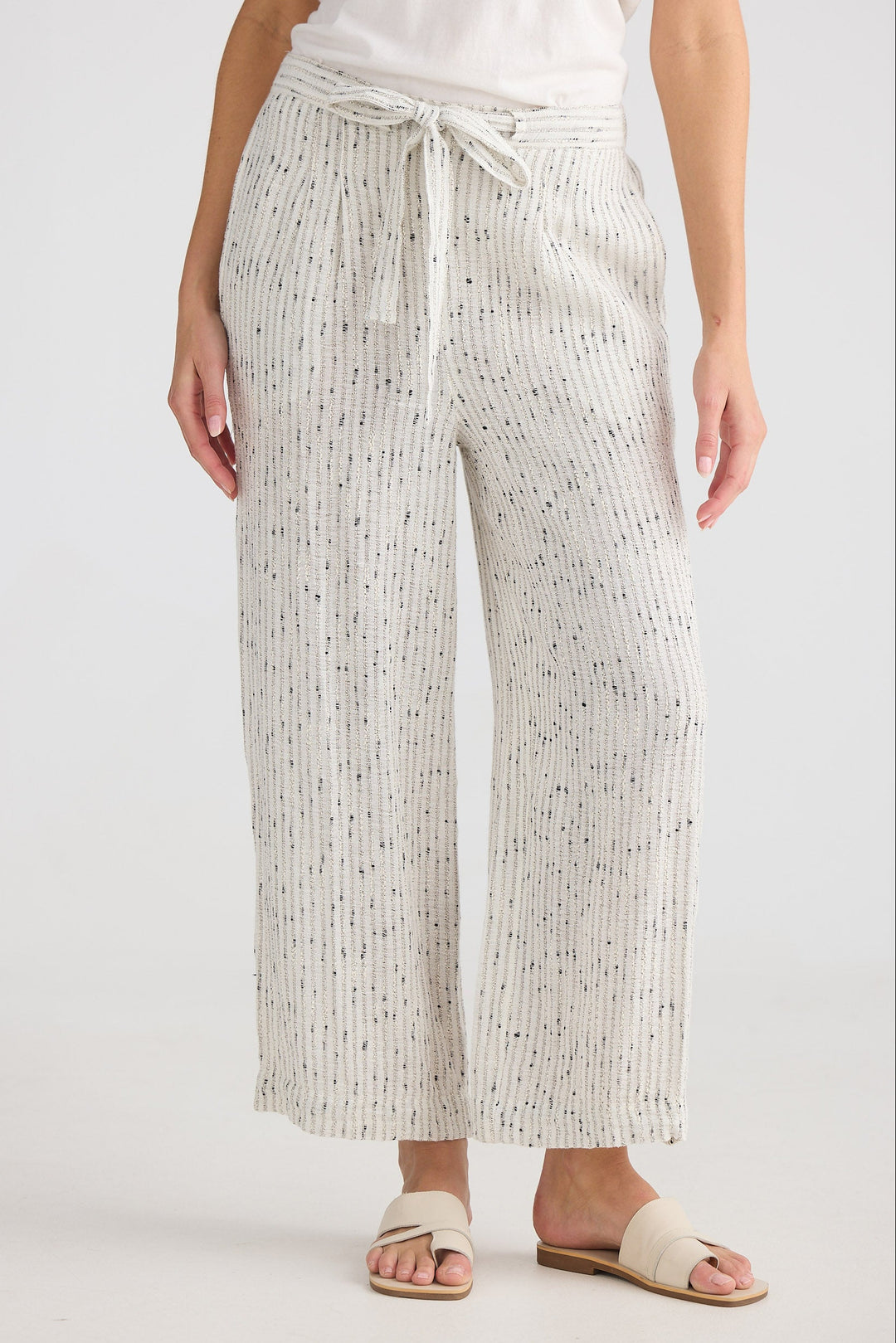 Person wearing white pants with a subtle pattern on a plain background