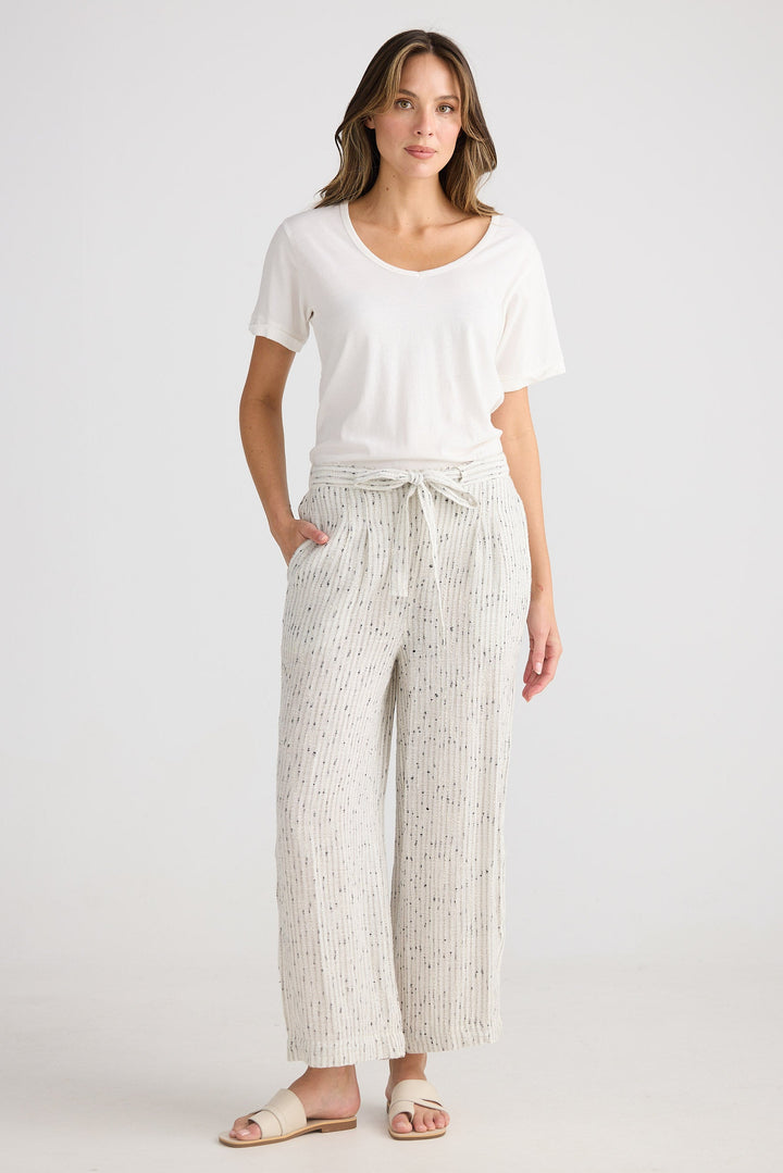 Woman wearing a white top and patterned pants on a white background