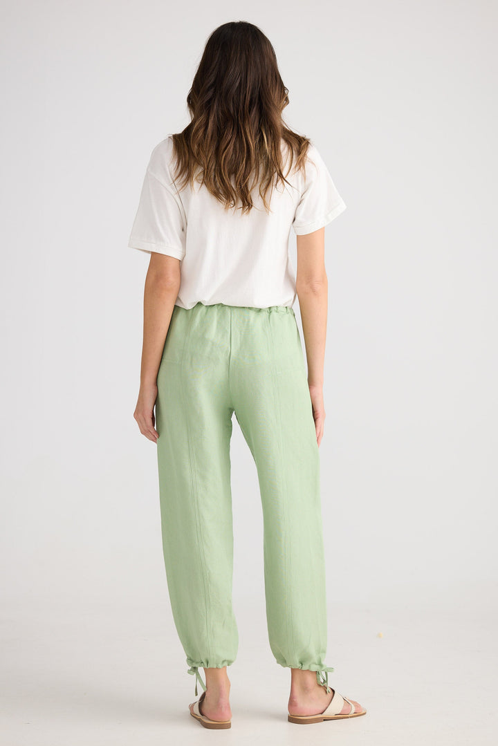 Person wearing a white shirt and light green pants on a plain background