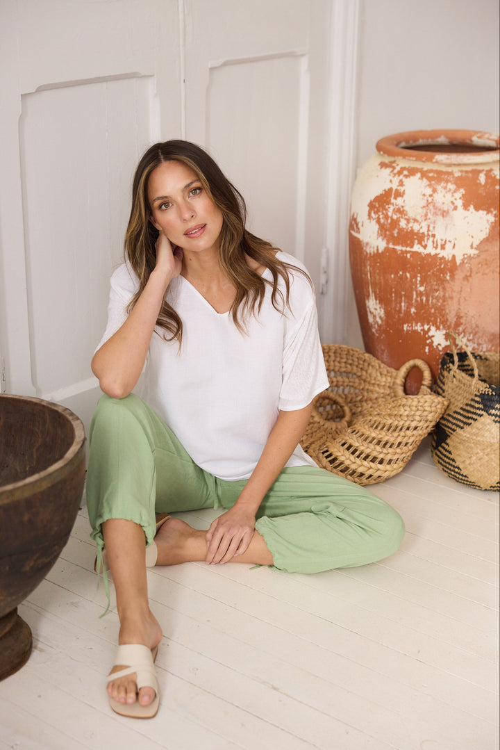 Woman sitting on the floor with wicker baskets and large pots in a minimalistic setting