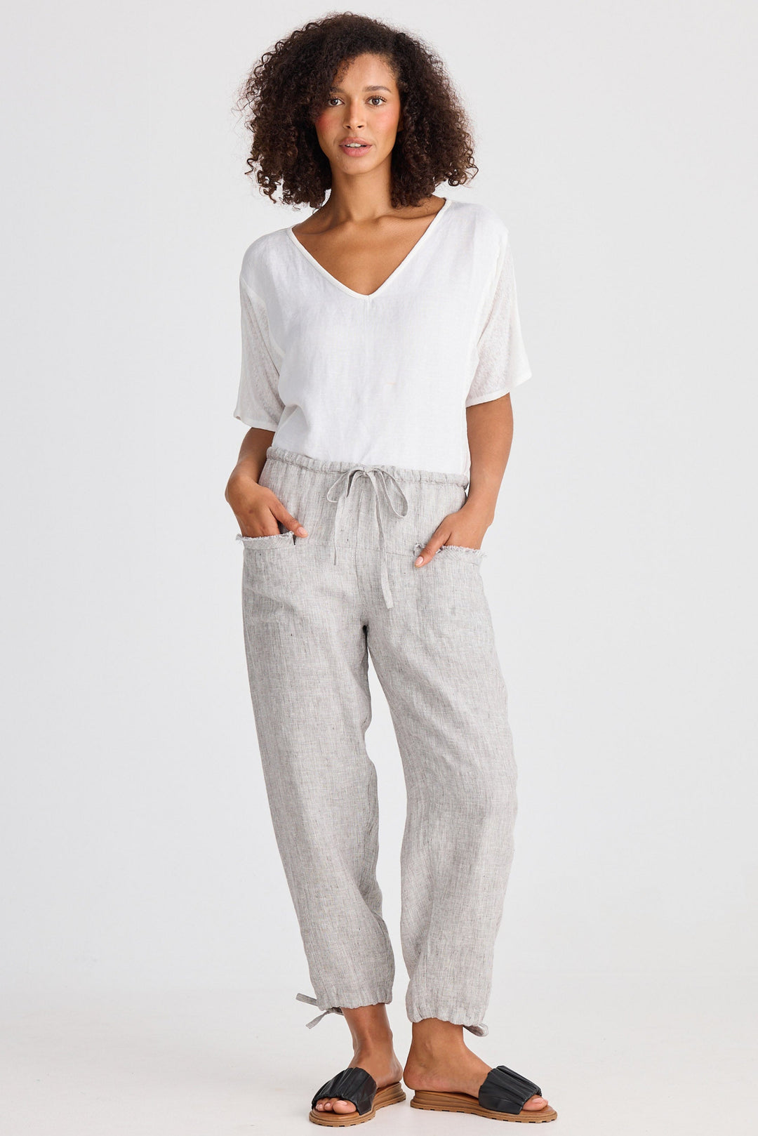 Woman wearing a white top and gray pants on a white background