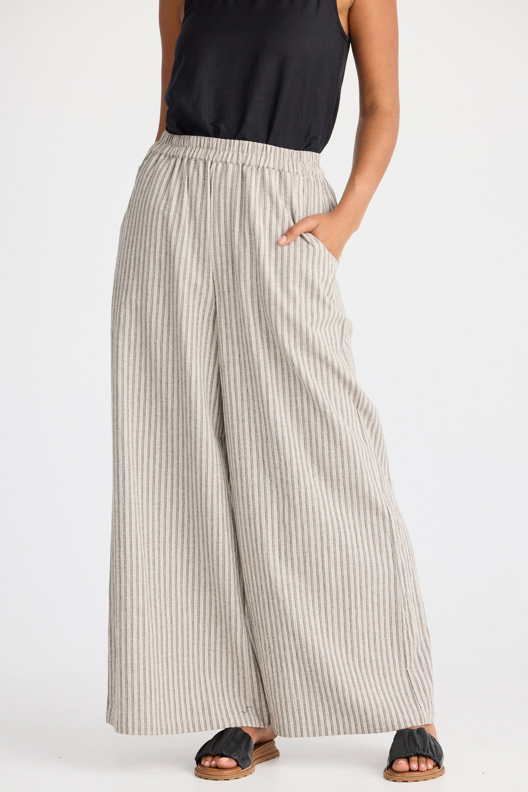 Person wearing wide-leg striped pants and black sandals on a white background