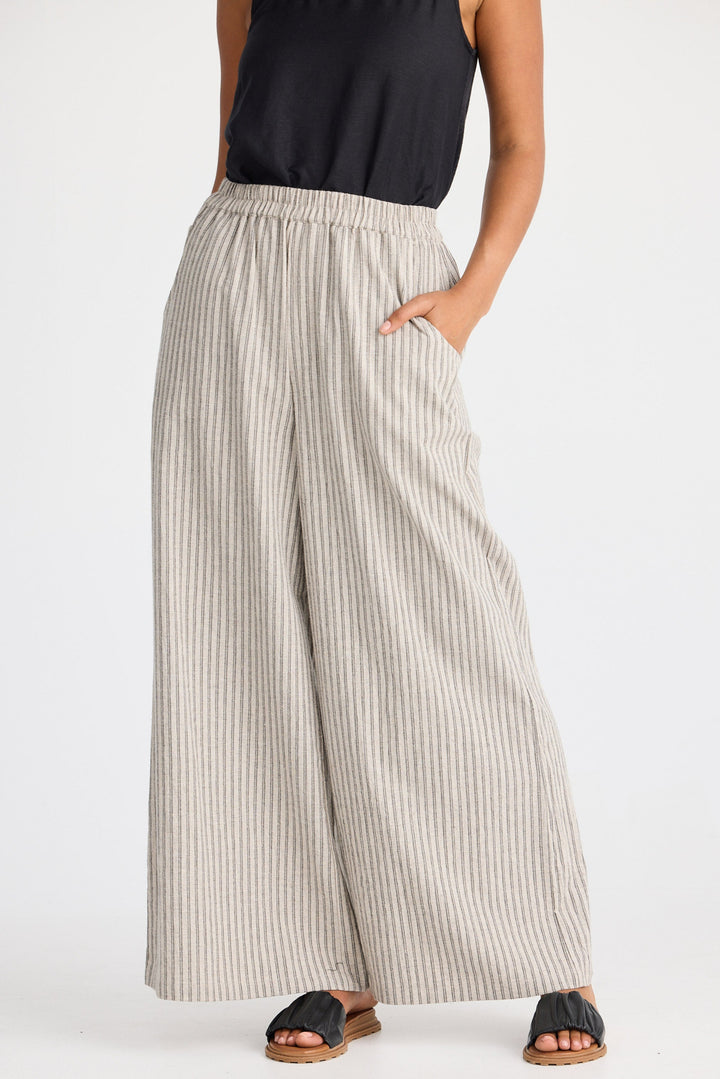 Person wearing wide-leg striped pants and black sandals on a white background