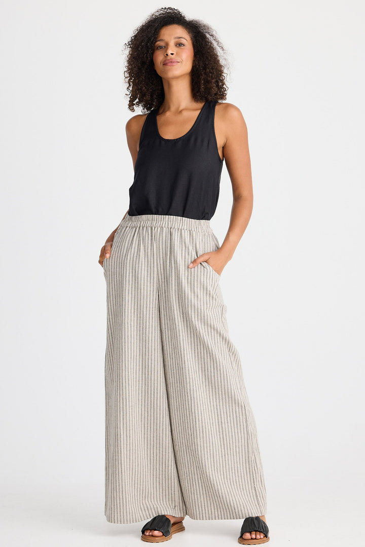 Woman wearing a black sleeveless top and striped pants on a white background