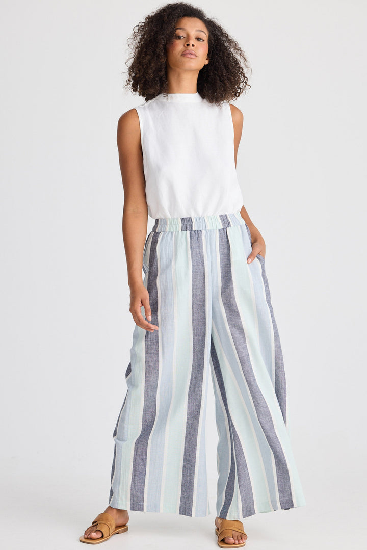 Woman wearing a white sleeveless top and striped wide-leg pants on a white background