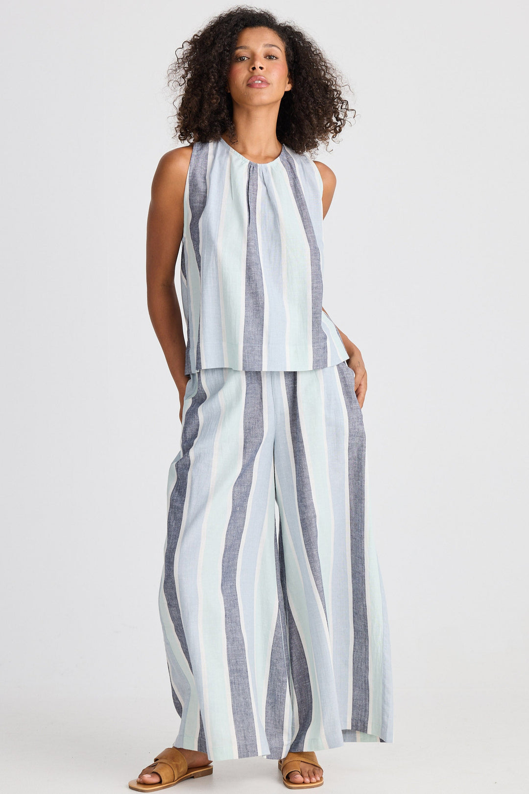 Woman wearing a striped sleeveless top and wide-leg pants on a white background