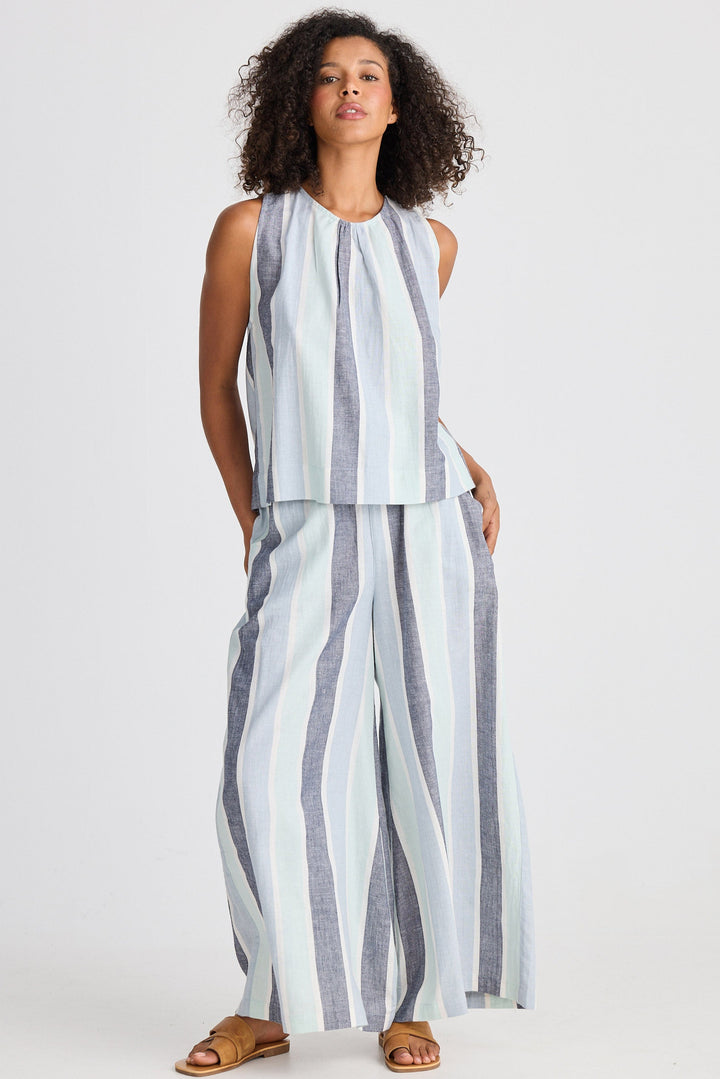 Woman wearing a striped sleeveless top and wide-leg pants on a white background