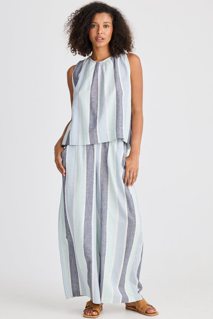 Woman wearing a sleeveless striped top and wide-leg pants on a white background