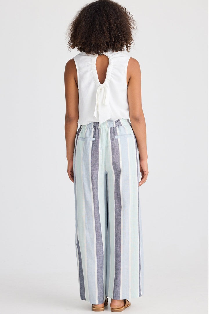Woman wearing a white sleeveless top and striped pants on a plain background