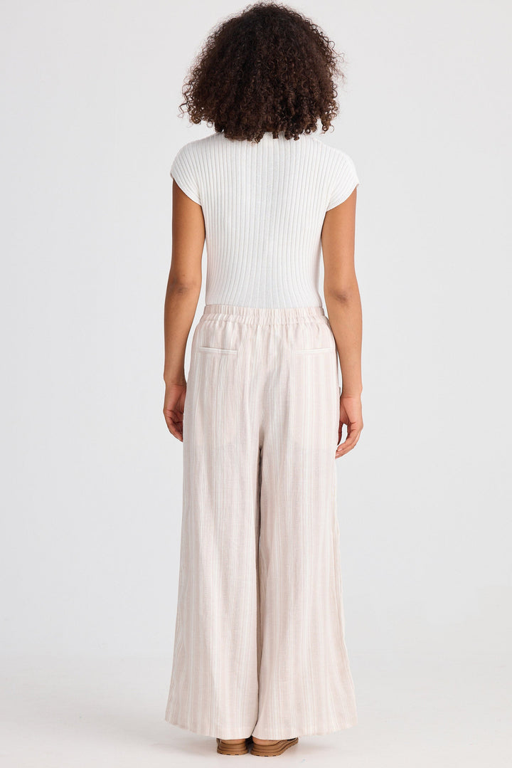 Person wearing a white top and beige striped wide-leg pants on a white background