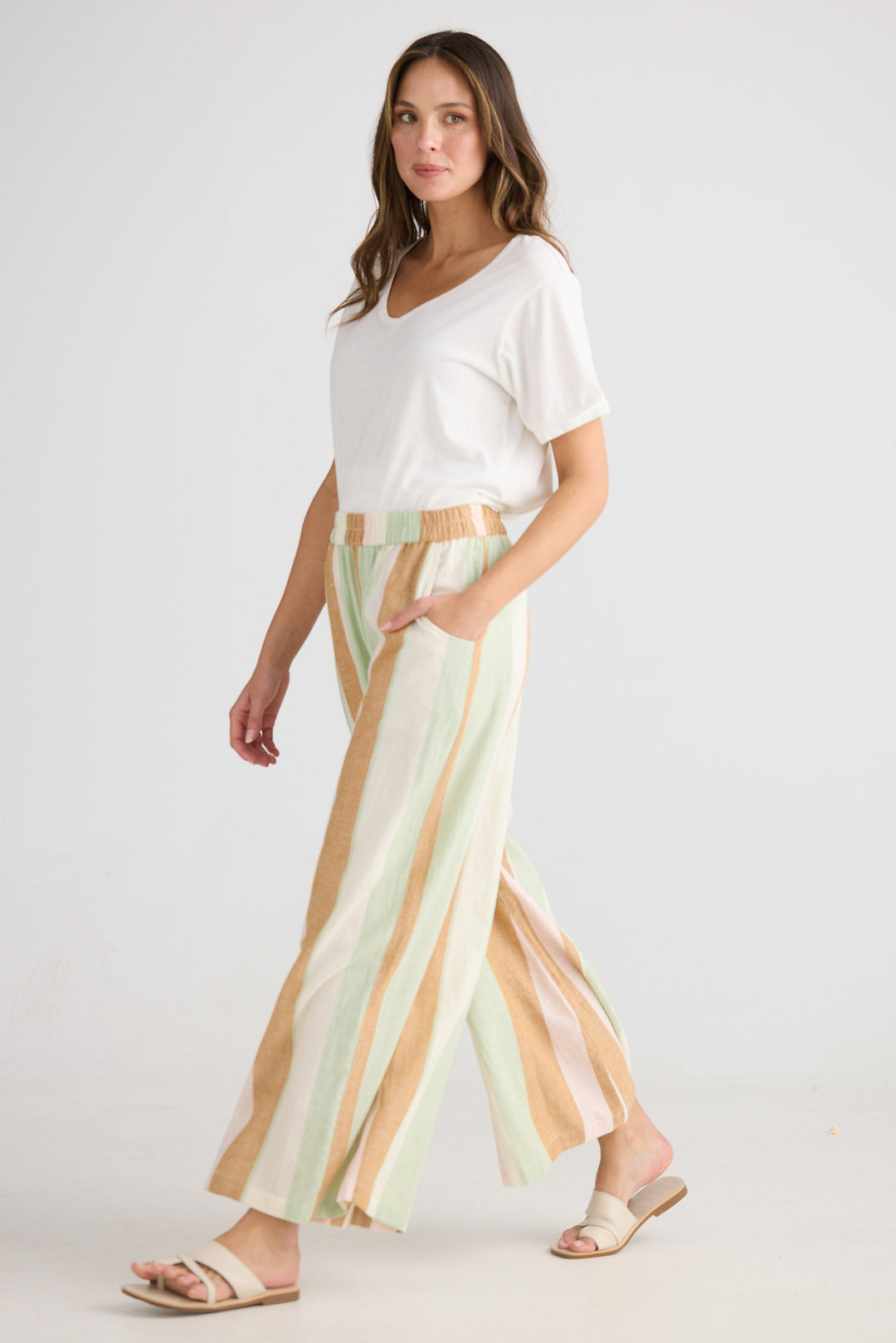 Woman wearing a white top and striped pants on a plain background