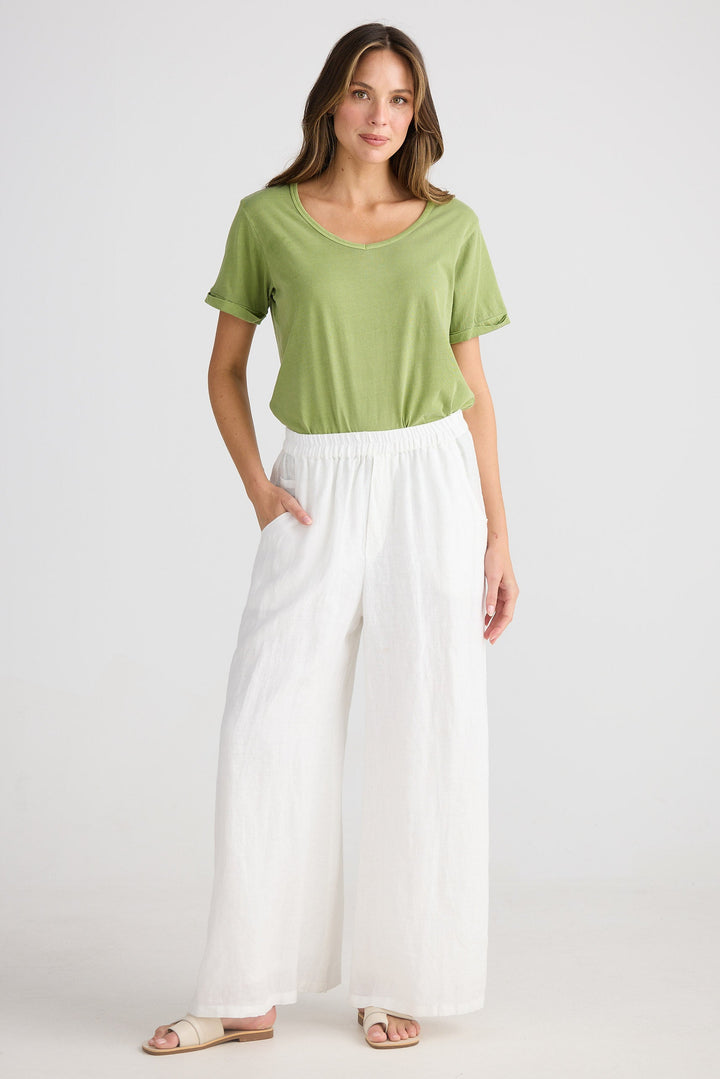 Woman wearing a green top and white pants on a white background