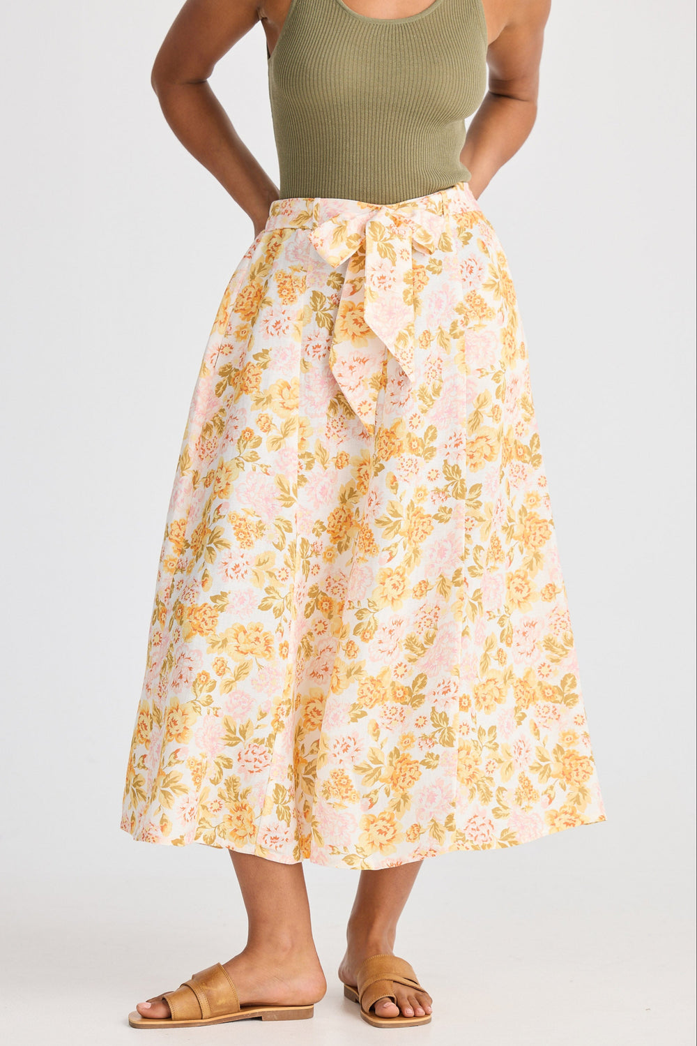 Person wearing a floral skirt and green top on a white background