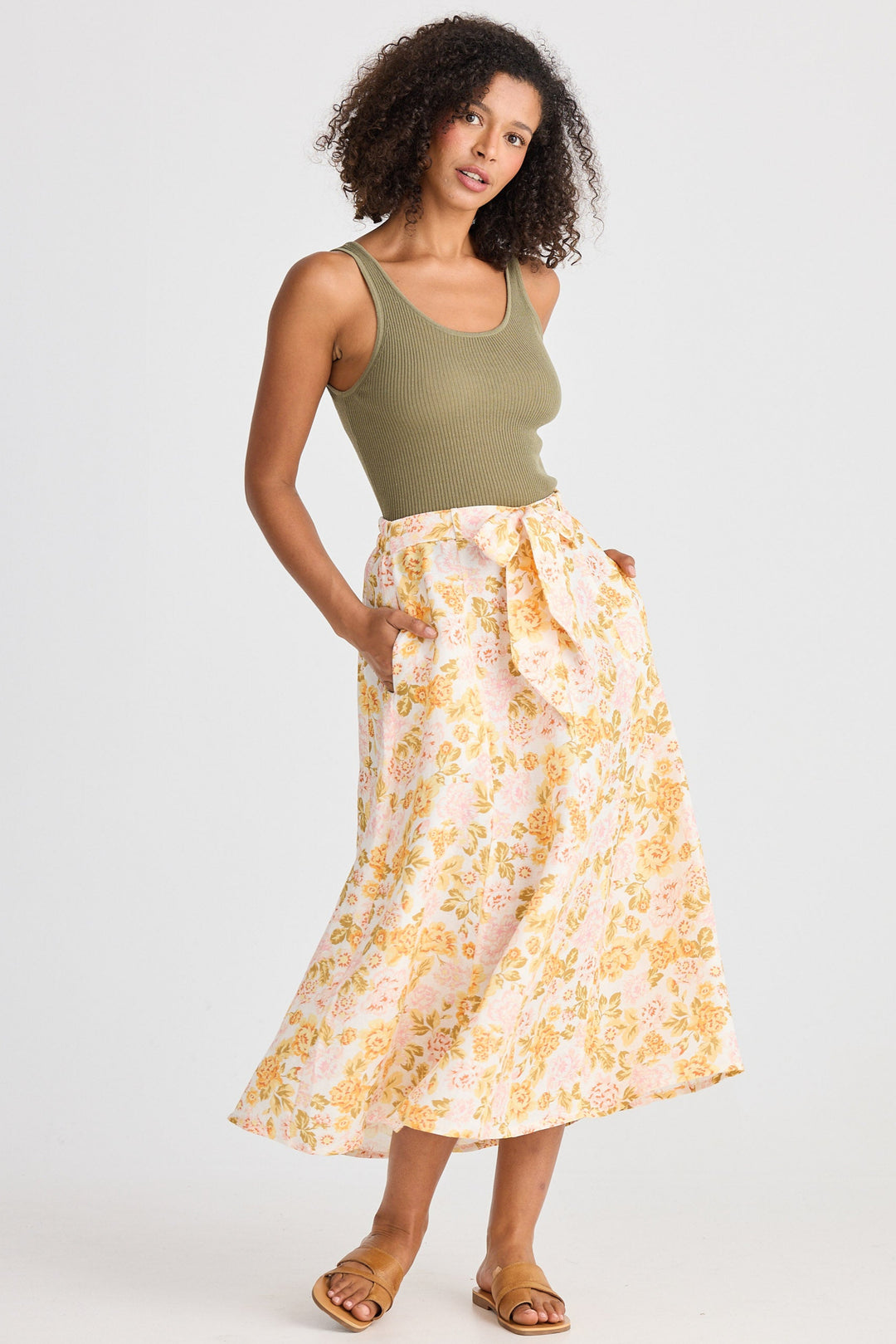 Woman wearing a green tank top and floral skirt on a white background