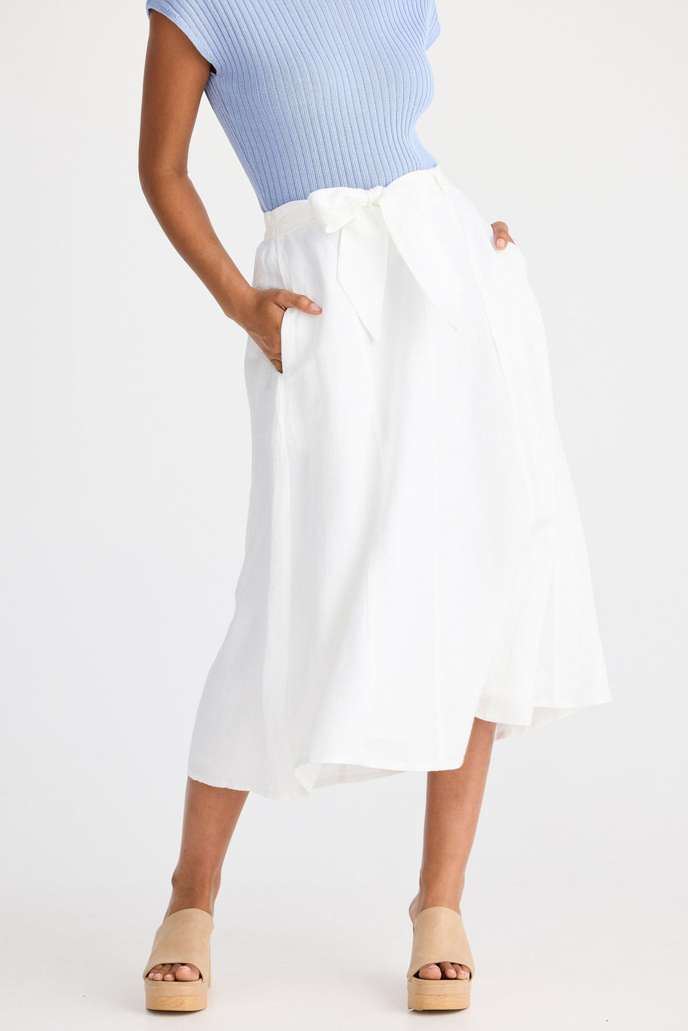 Person wearing a light blue top and white skirt on a white background