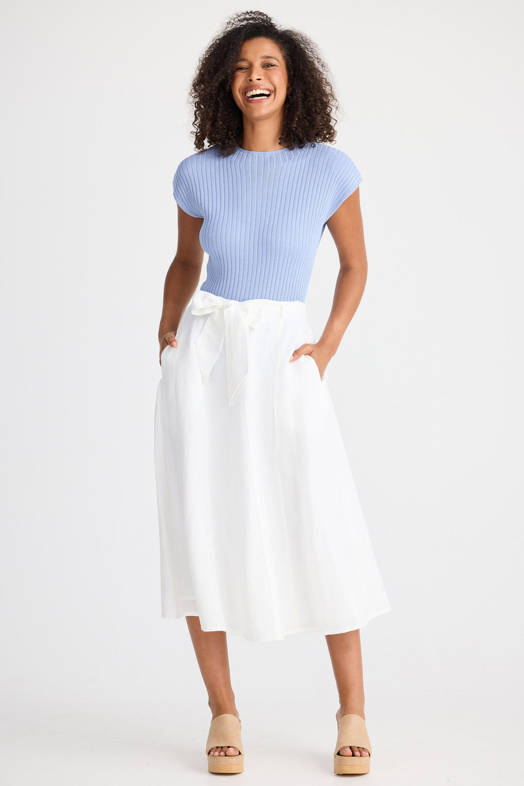 Woman wearing a light blue top and white skirt on a white background