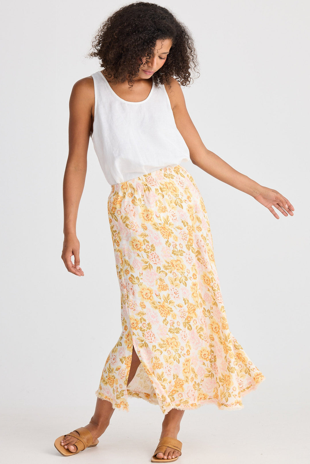 Woman wearing a white sleeveless top and floral skirt on a white background