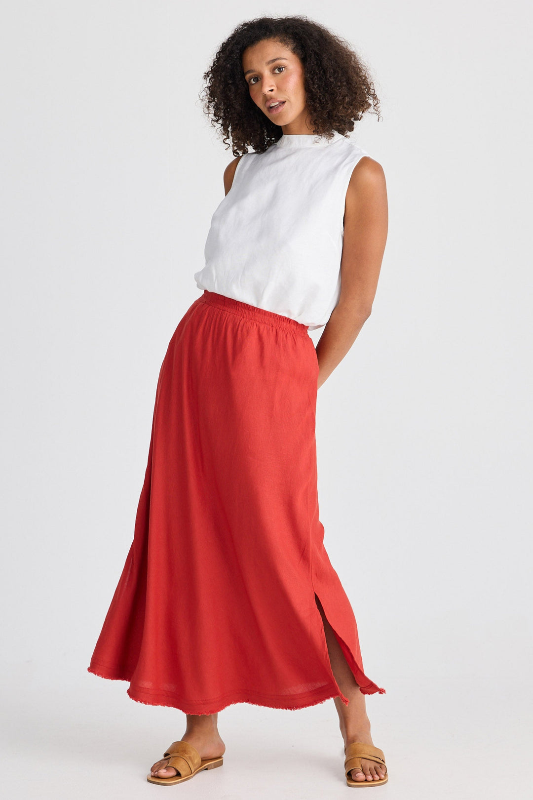 Woman wearing a white sleeveless top and red skirt on a white background