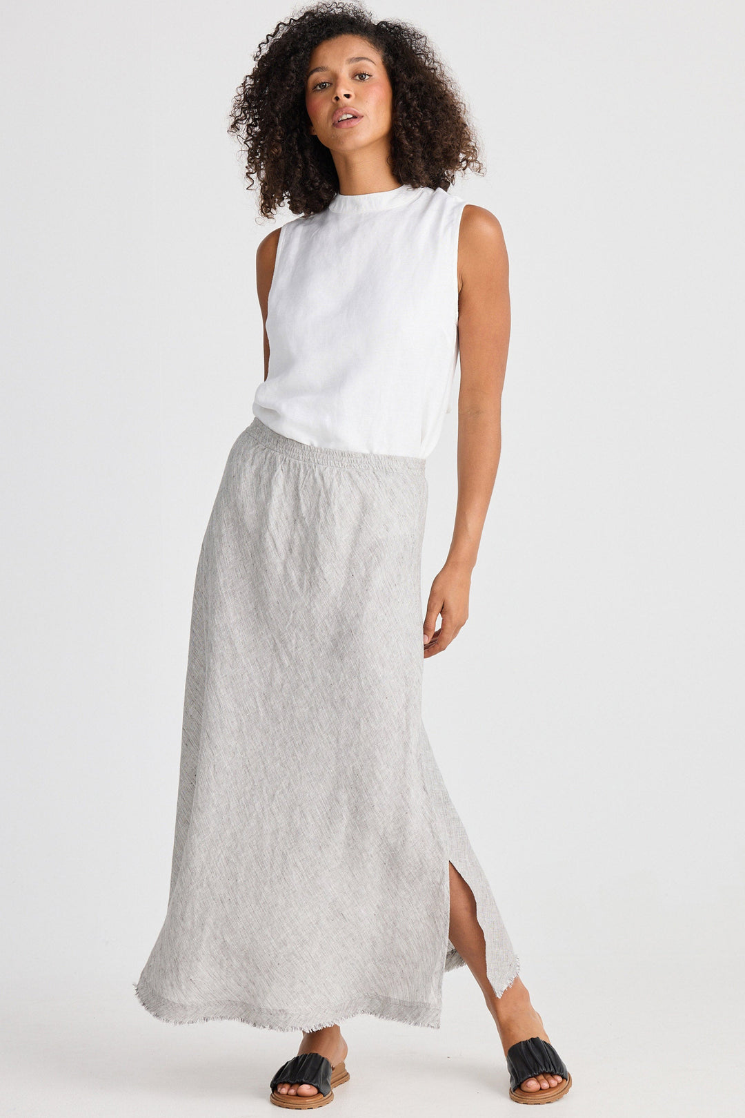 Woman wearing a white sleeveless top and light gray skirt on a white background
