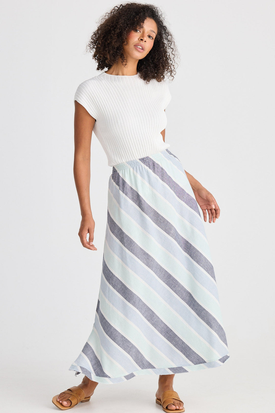 Woman wearing a white top and striped skirt on a white background