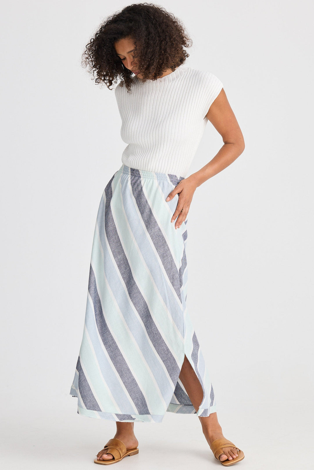 Woman wearing a white top and striped skirt on a white background