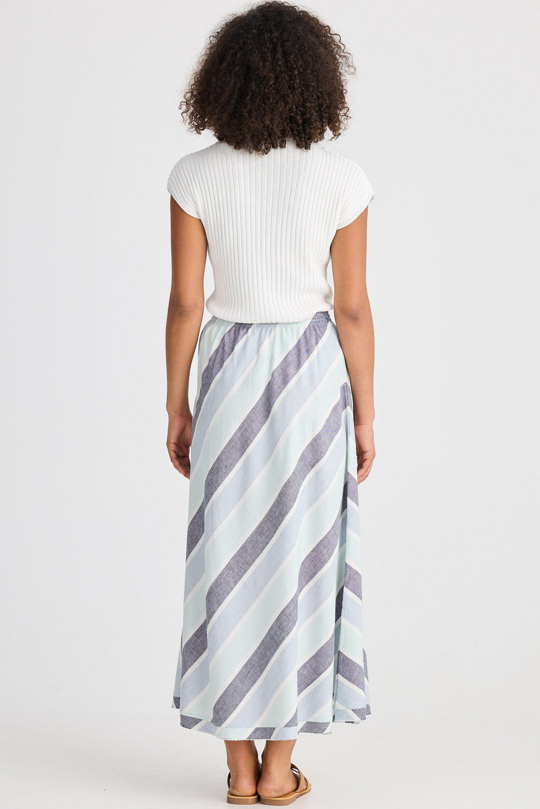 Person wearing a white top and striped skirt on a plain background