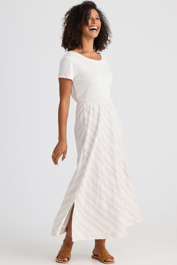 Woman wearing a white top and light striped skirt on a white background