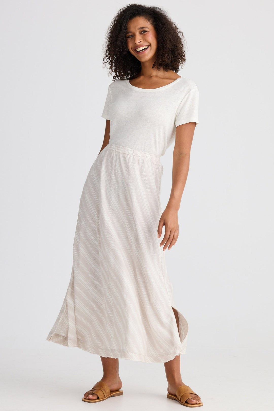 Woman wearing a white top and light striped skirt on a plain background