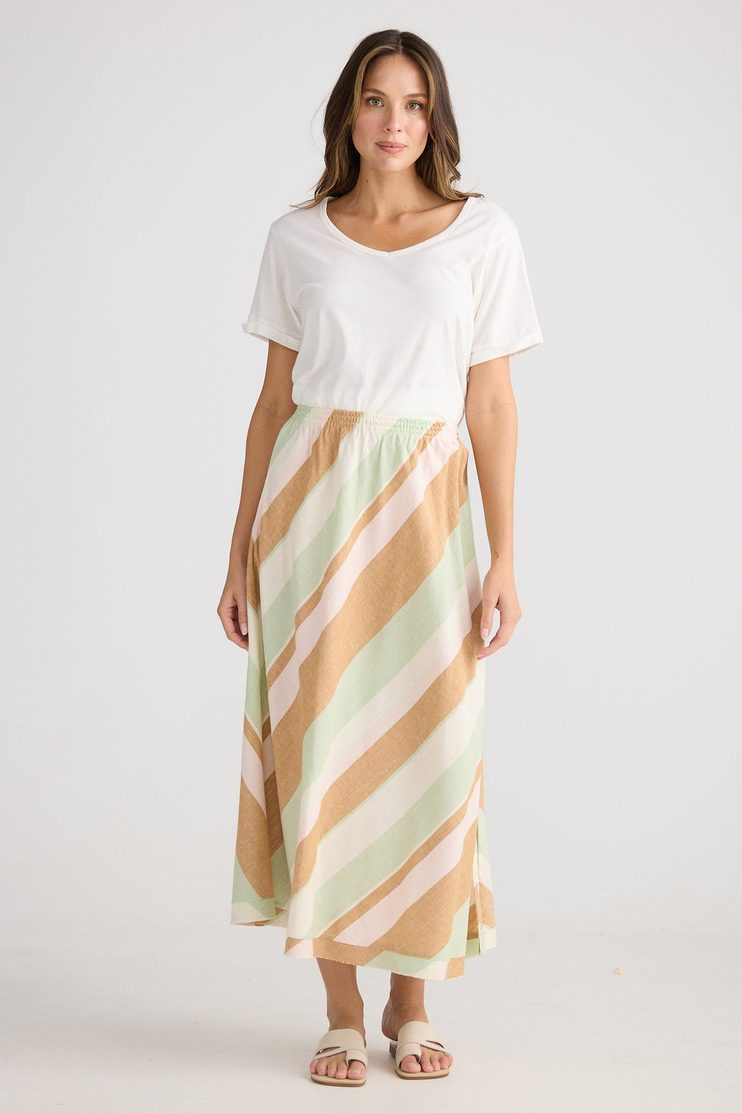 Woman wearing a white top and striped skirt on a plain background