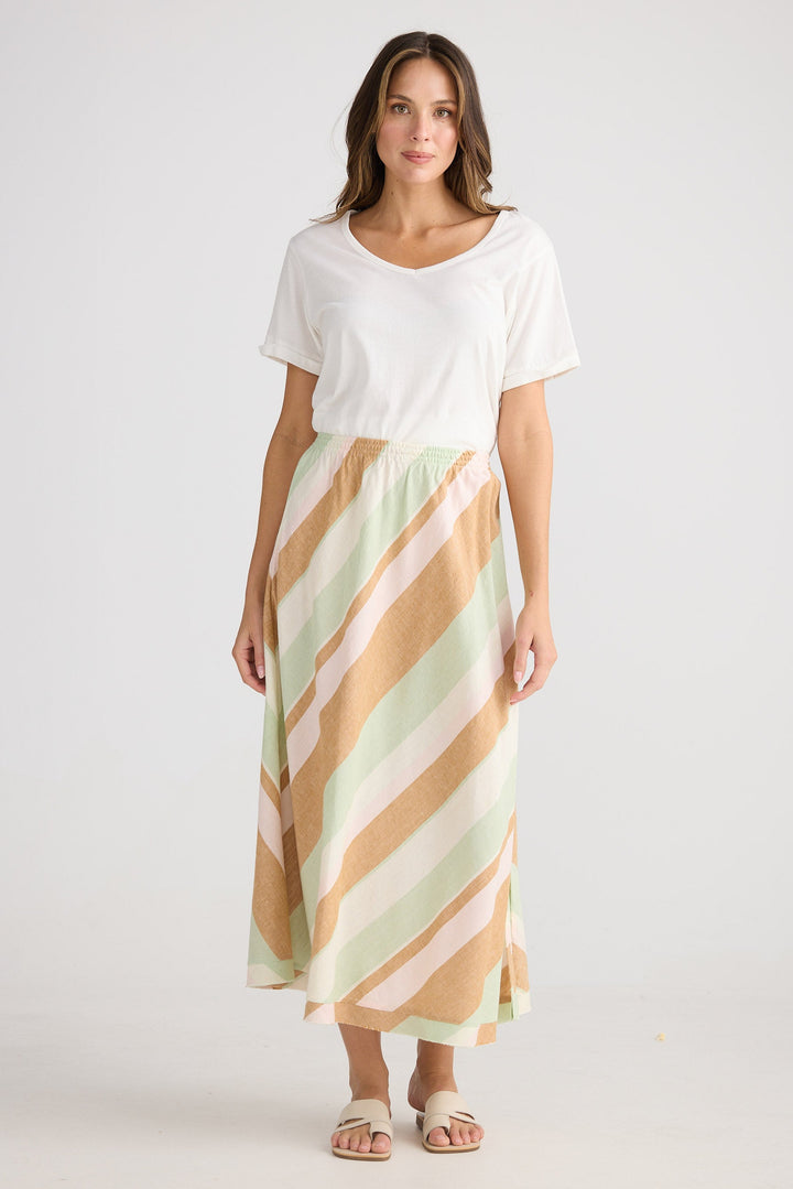 Woman wearing a white top and striped skirt on a plain background