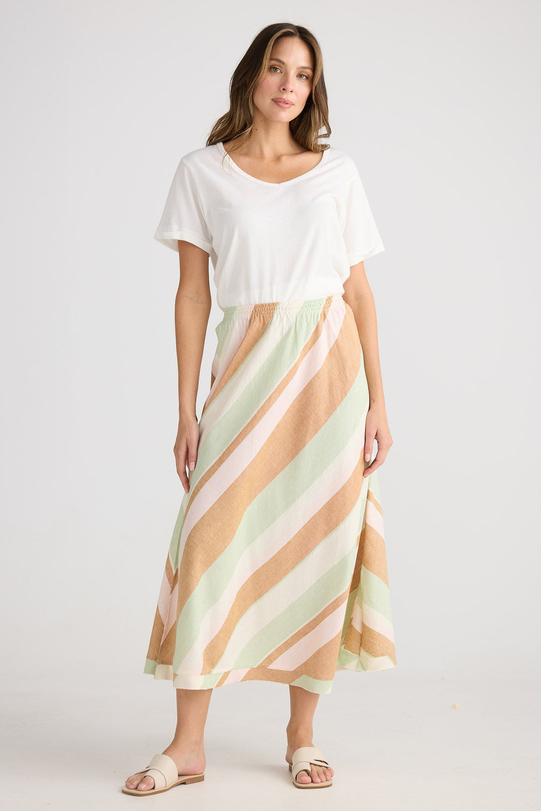 Woman wearing a white top and a striped skirt on a plain background