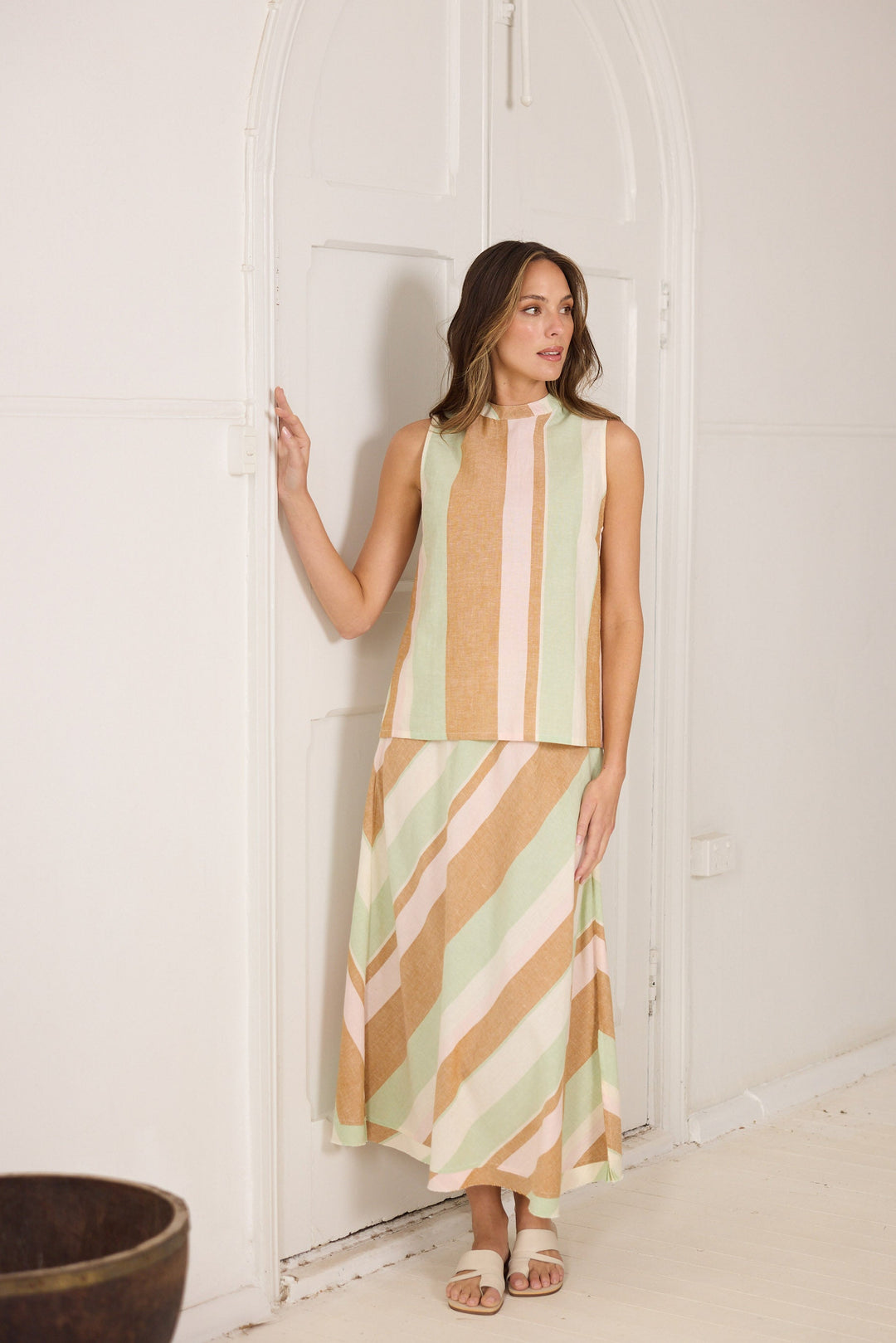 Woman wearing a striped top and skirt standing in a doorway.