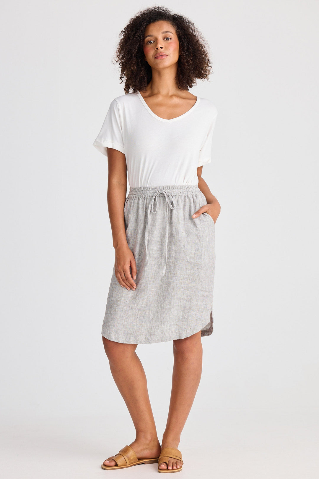 Woman wearing a white top and gray skirt on a white background