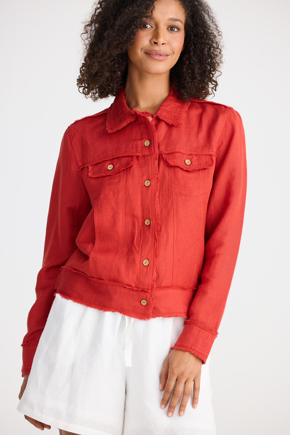 Woman wearing a red jacket over a white dress on a white background