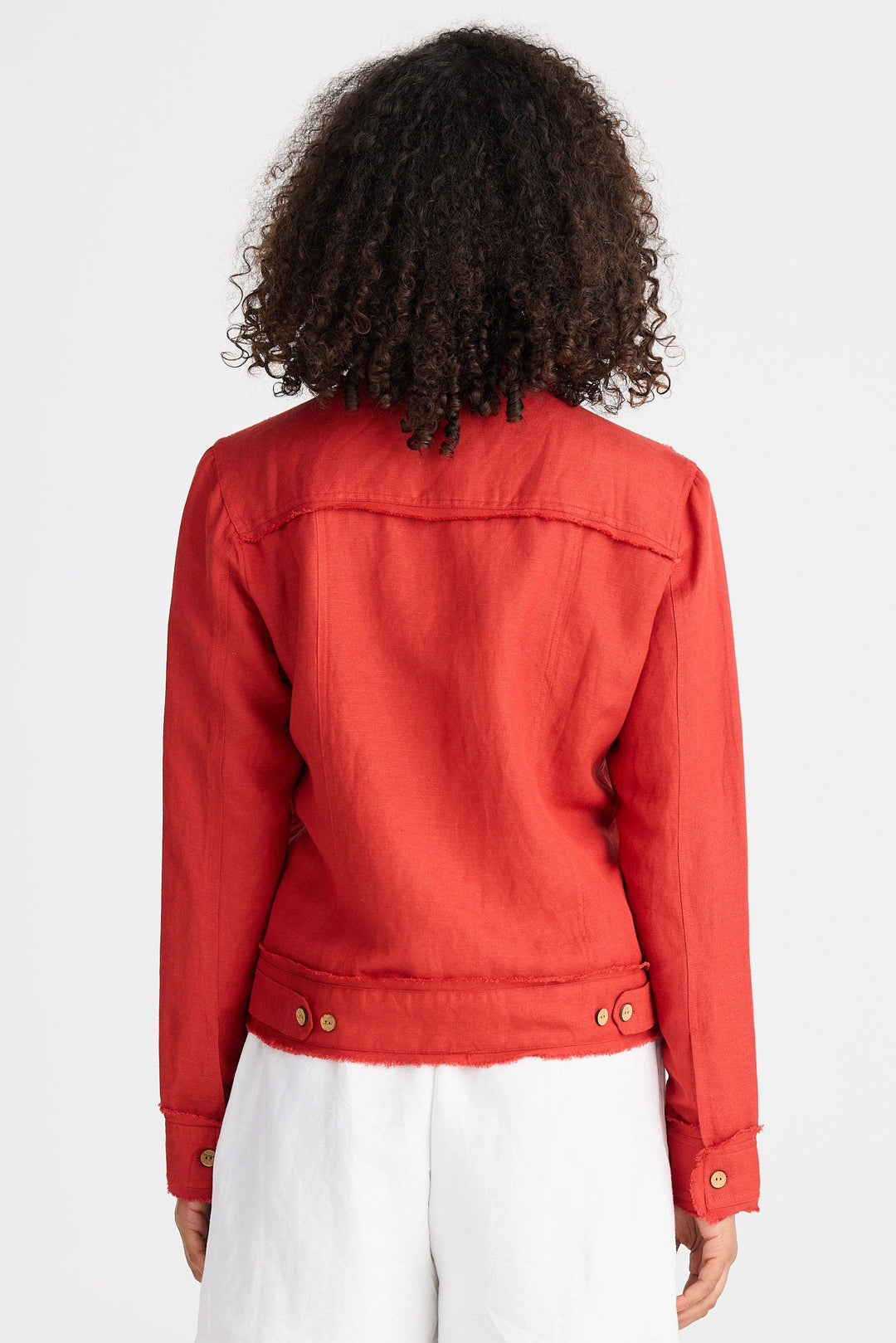 Person wearing a red jacket and white shorts on a plain background