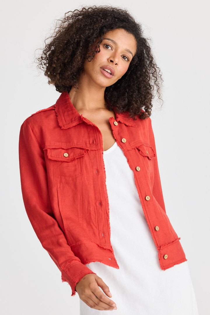Woman wearing a red jacket over a white dress on a light gray background