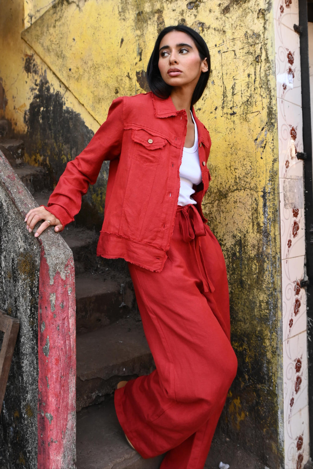 Person in a red outfit standing in front of a yellow surface with a textured background