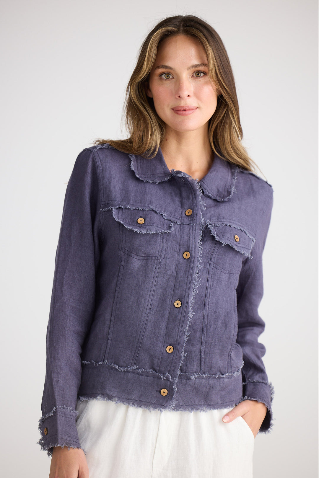 Woman wearing a navy jacket with ruffled collar on a white background