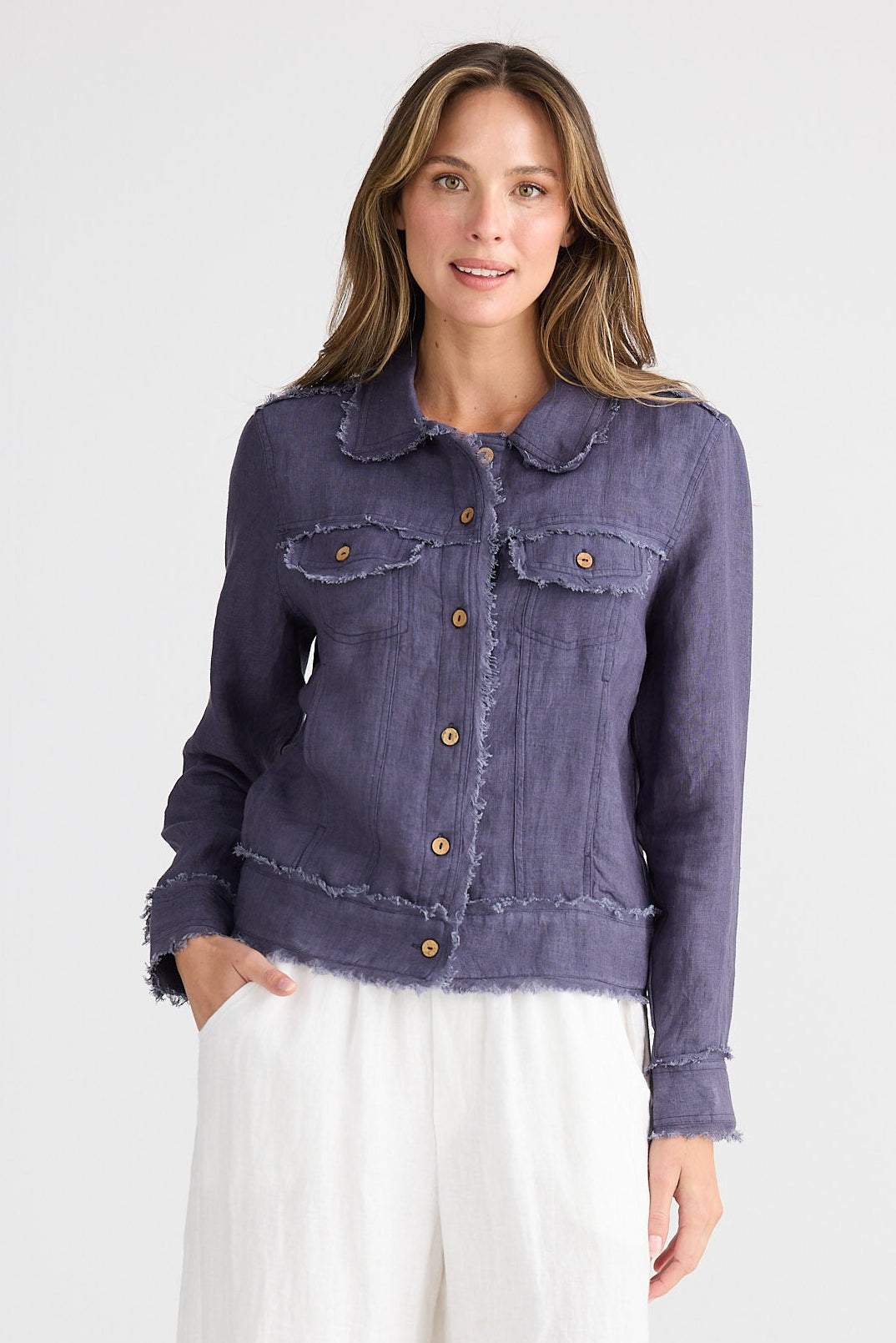 Woman wearing a navy jacket and white pants on a white background