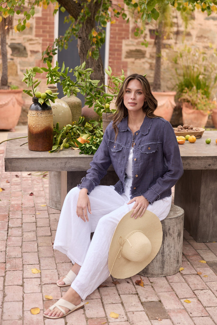 Woman sitting outdoors on a stone bench with a garden and table in the background