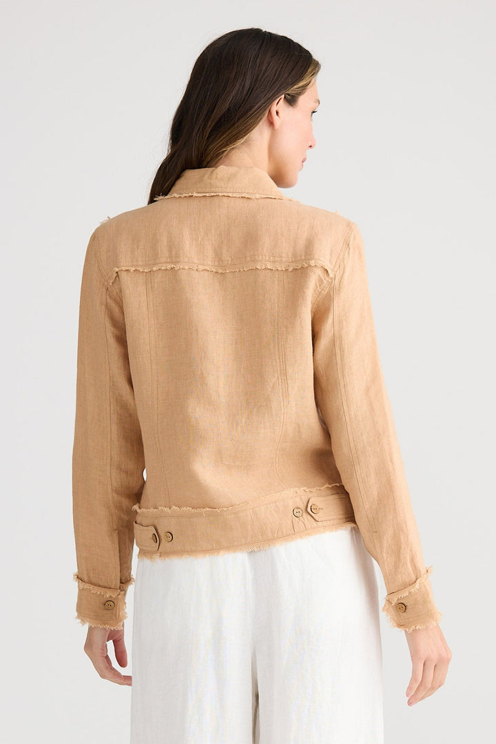 Woman wearing a beige jacket and white pants on a plain background