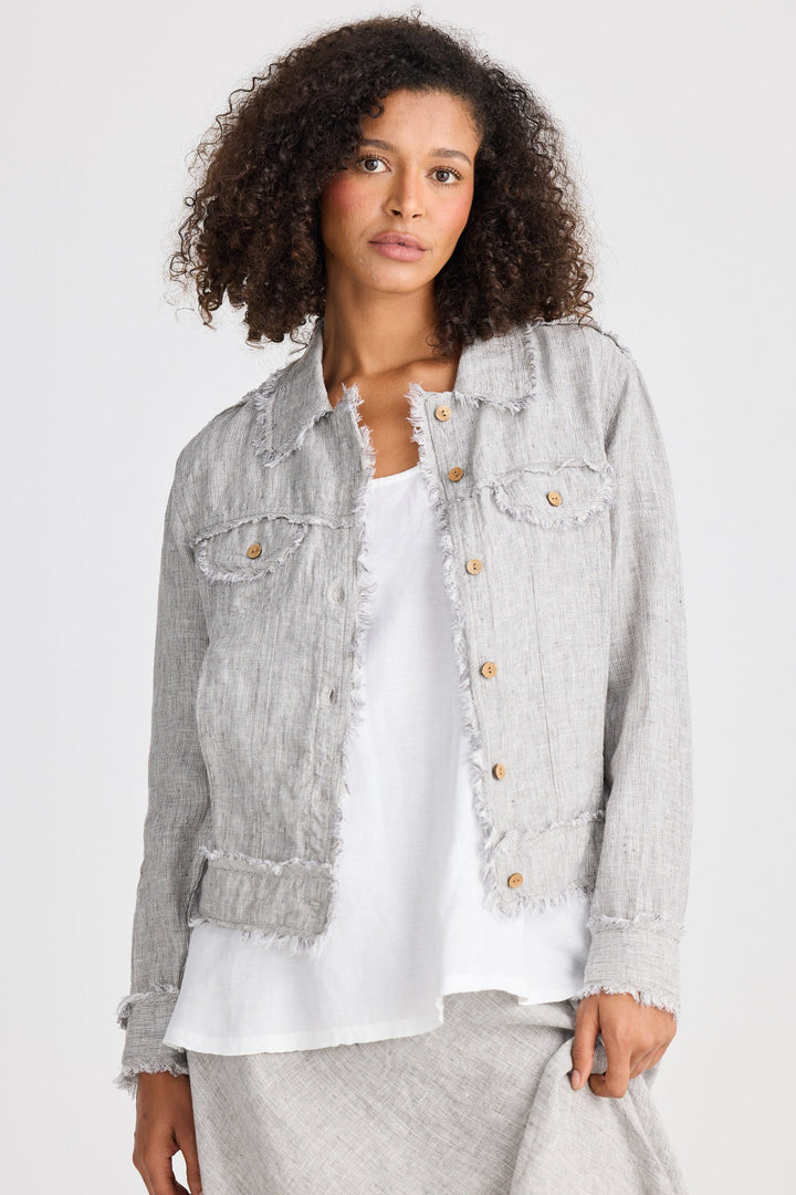Woman wearing a light gray jacket over a white shirt on a plain background