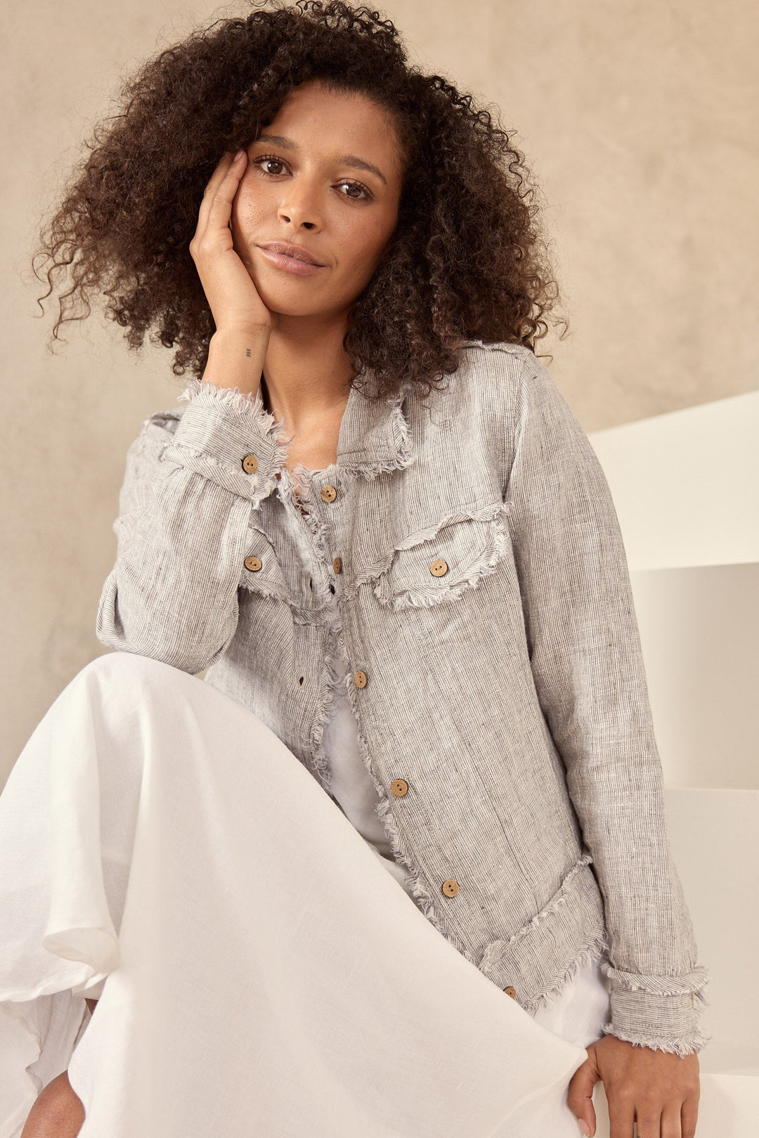 Woman wearing a light gray jacket with lace details on a neutral background