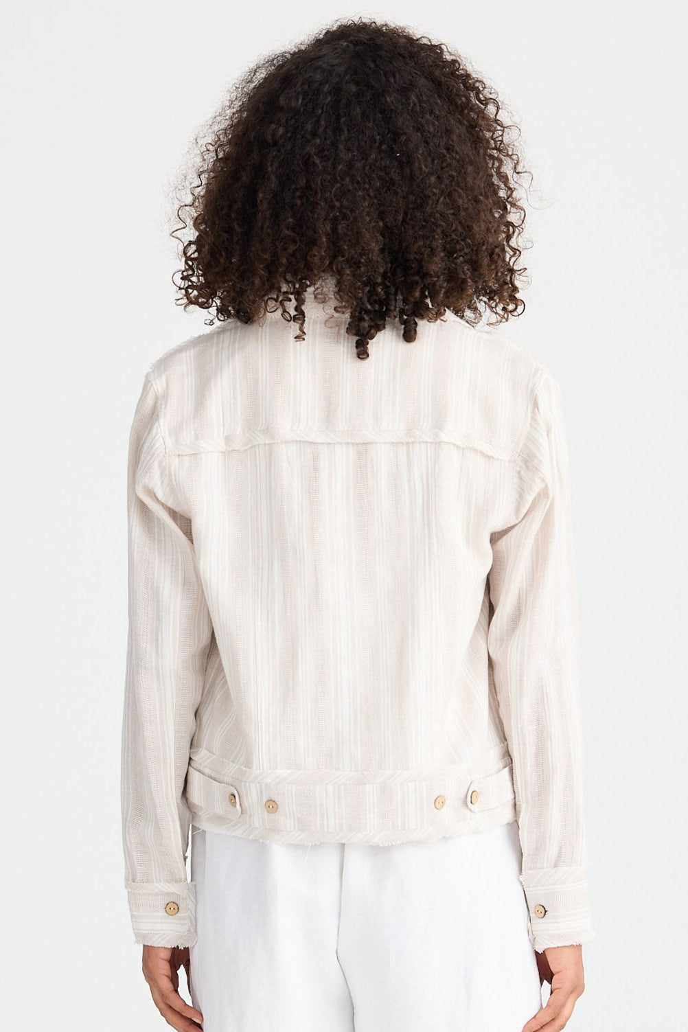 Person wearing a light-coloured jacket and white shorts on a white background
